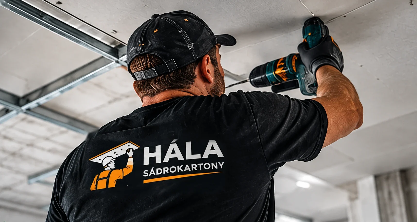 Pracovník montuje sádrokartonový strop, viditelné logo HÁLA na zádech